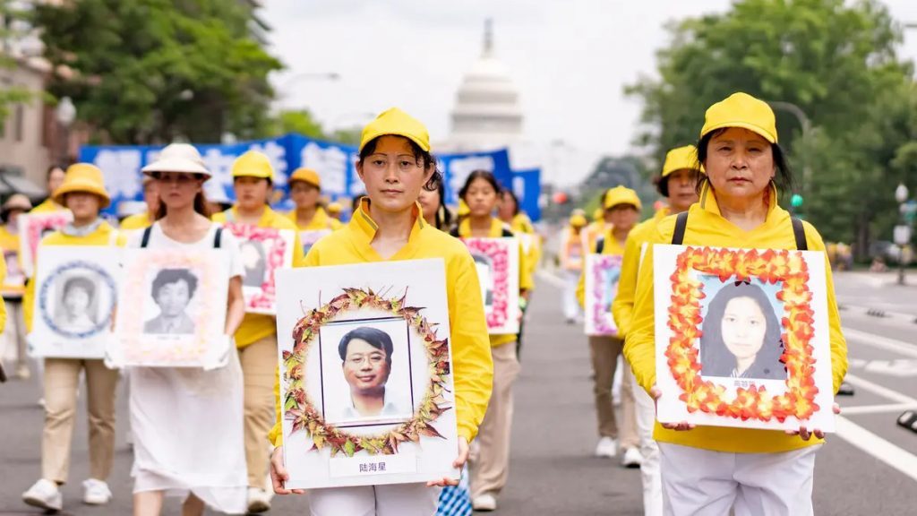Practitioners in yellow march in Washington, DC carrying framed portraits of persecution victims, the US Capitol behind