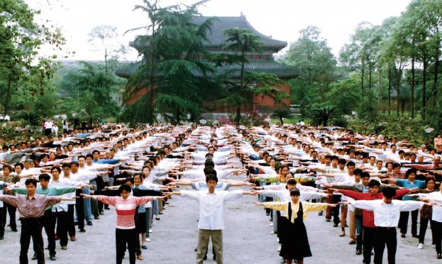 Hundreds of people practising Falun Dafa exercises in rows before a temple in 1990s China